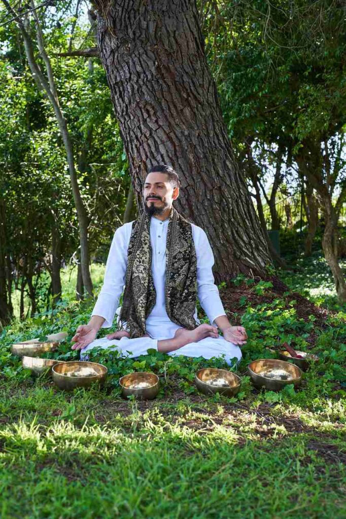 Francisco in seated Meditation Posture under a tree all in white
